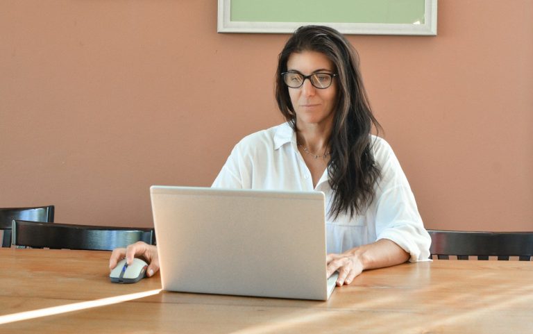 A woman wearing glasses works on a laptop